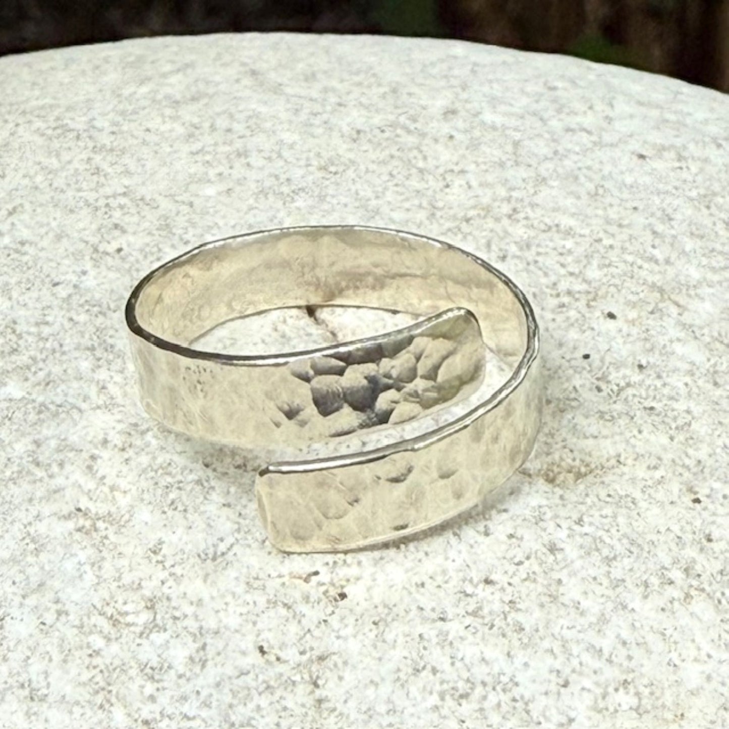 Silver ring with a textured surface on a light stone surface