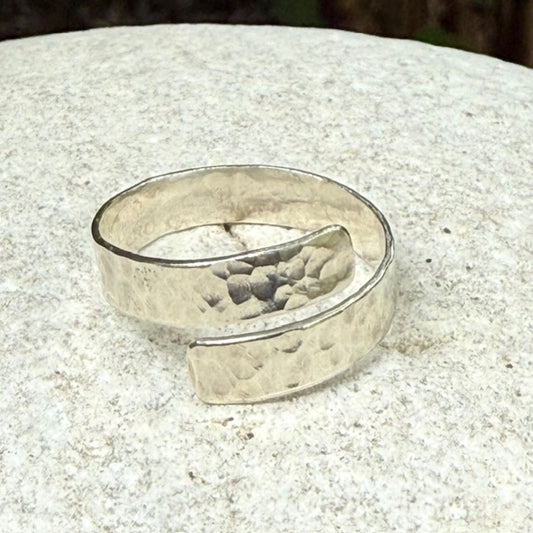 Silver ring with a textured surface on a light stone surface