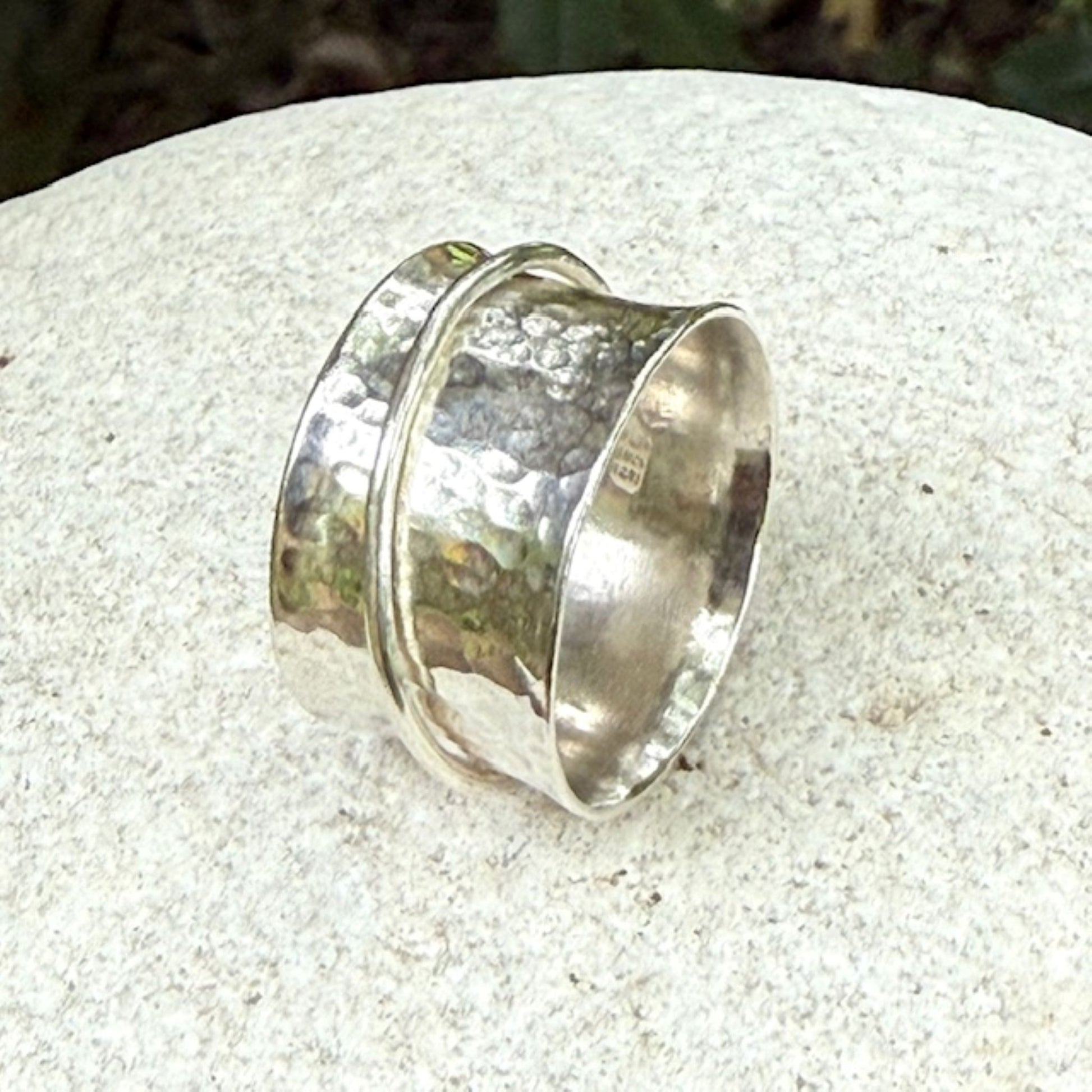 Silver spinning ring with a textured design on a light stone surface