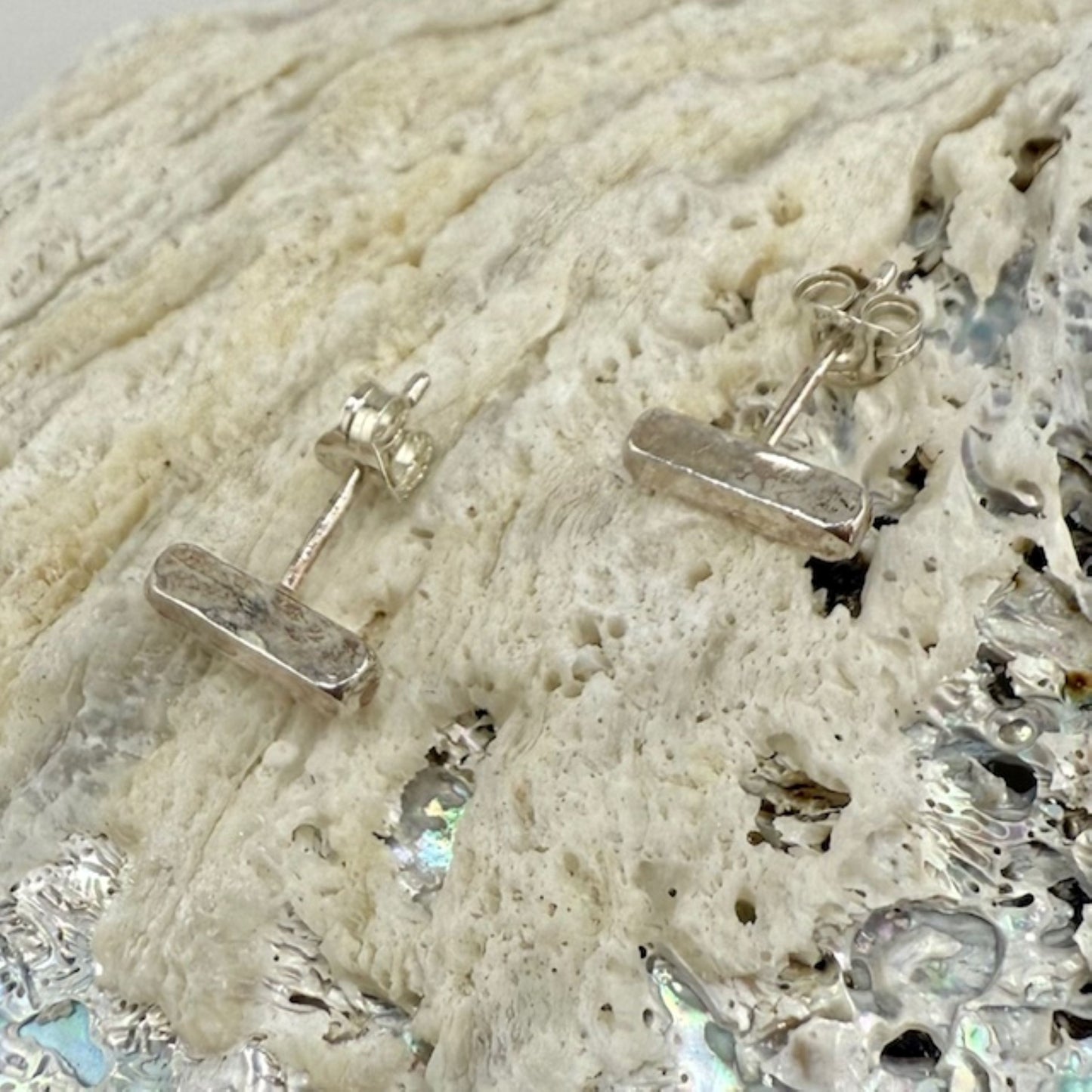 Silver bar studearrings on a textured shell surface