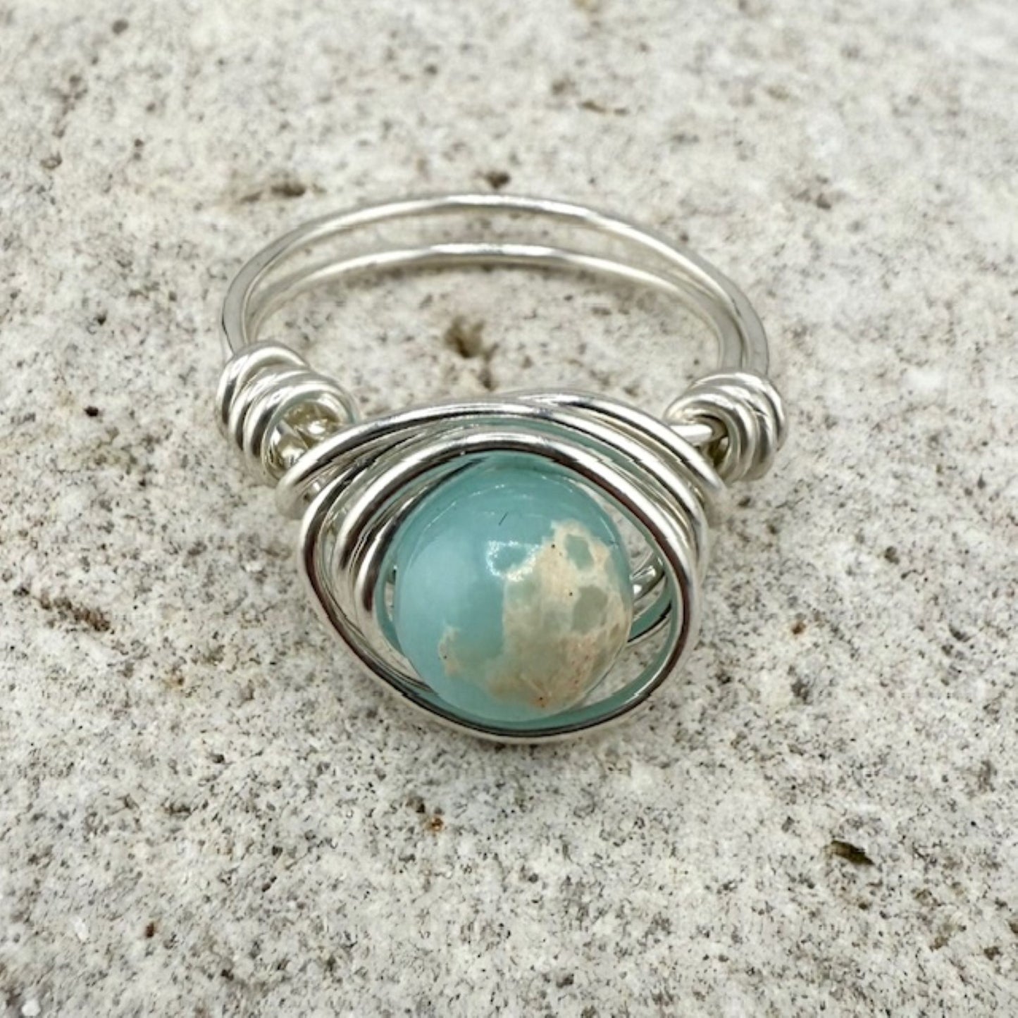Silver ring with a blue gemstone on a textured surface