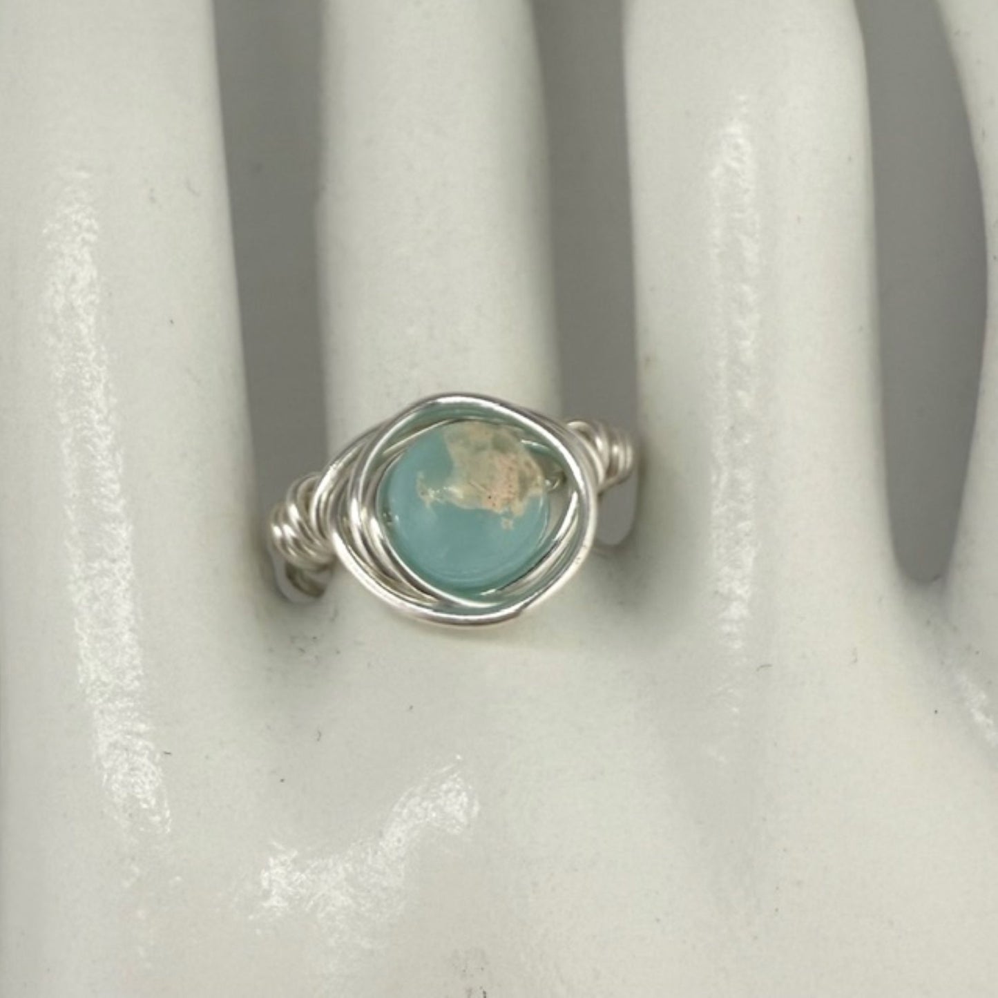 Silver ring with an aqua stone on a white marble hand display