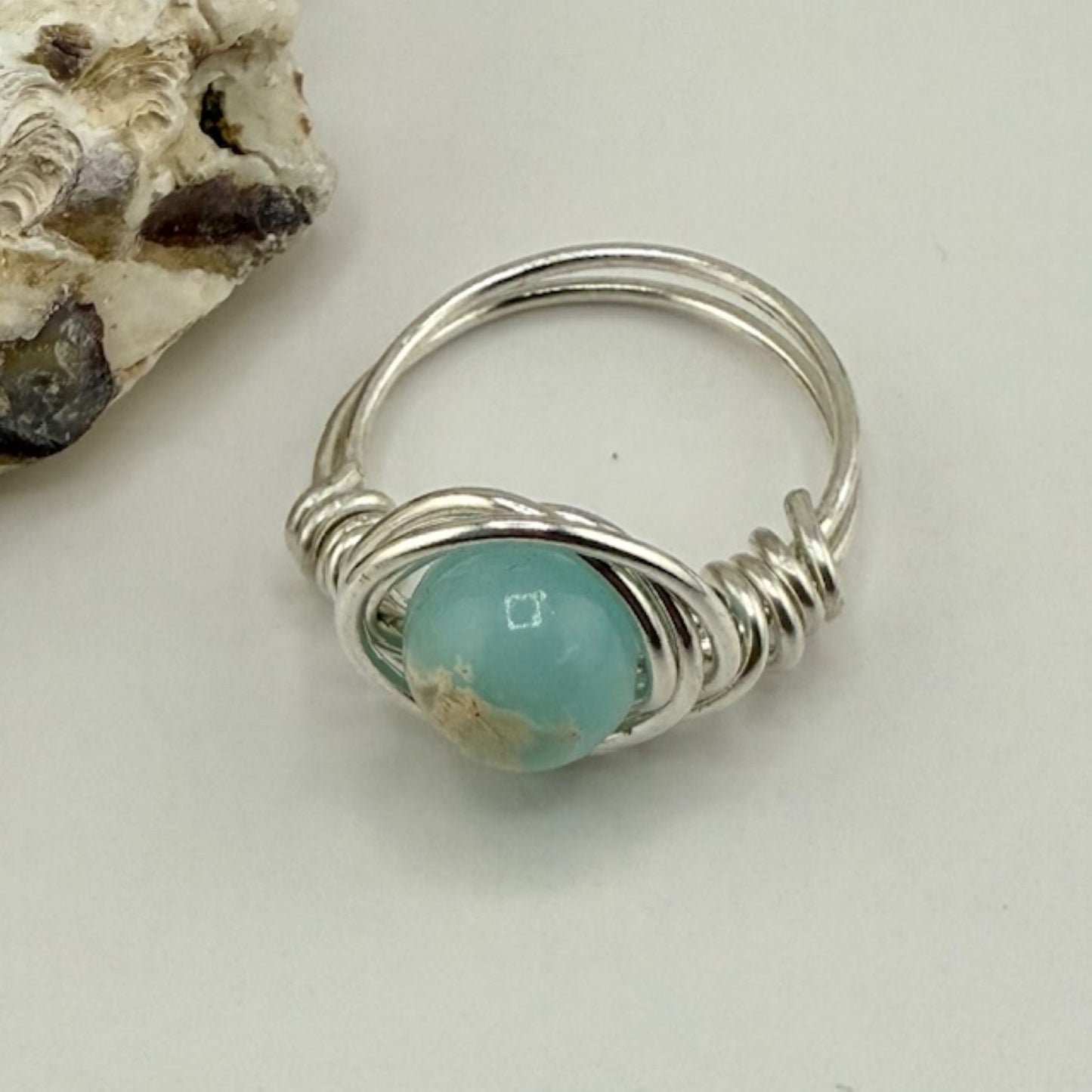 Silver ring with a blue green gemstone on a light background