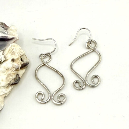 Silver wire earrings on a white background with a shell.