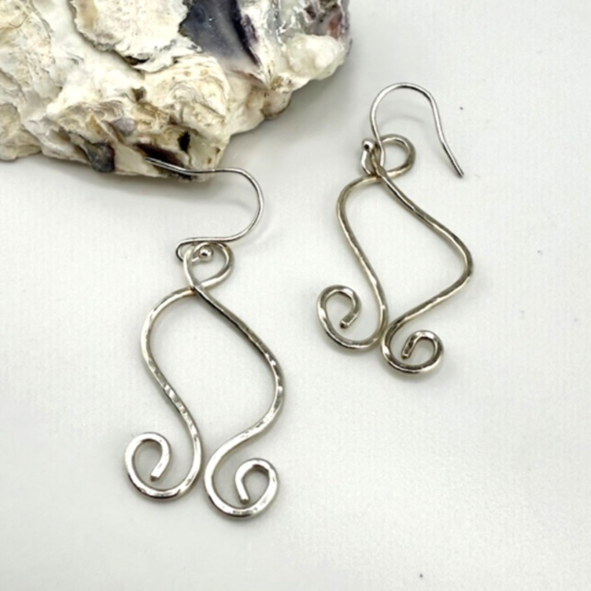 Silver wire earrings on a white background with a stone.