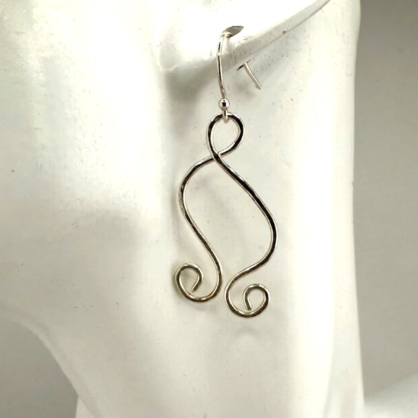 Silver wire earrings on a white mannequin