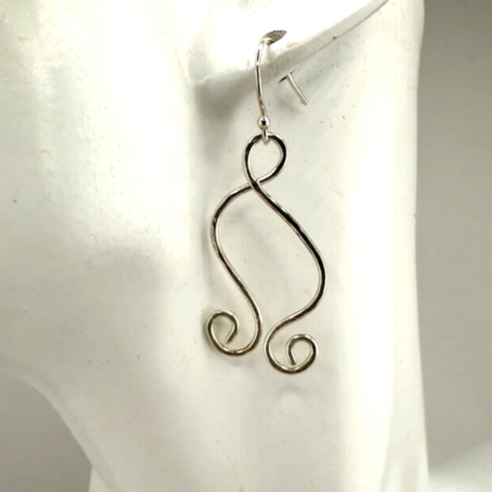 Silver wire earrings on a white mannequin