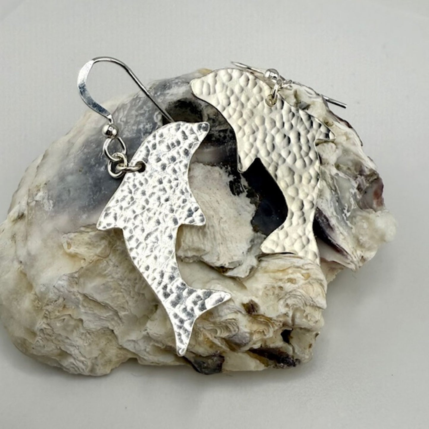 Hammered sterling Silver dolphin earrings on a rock