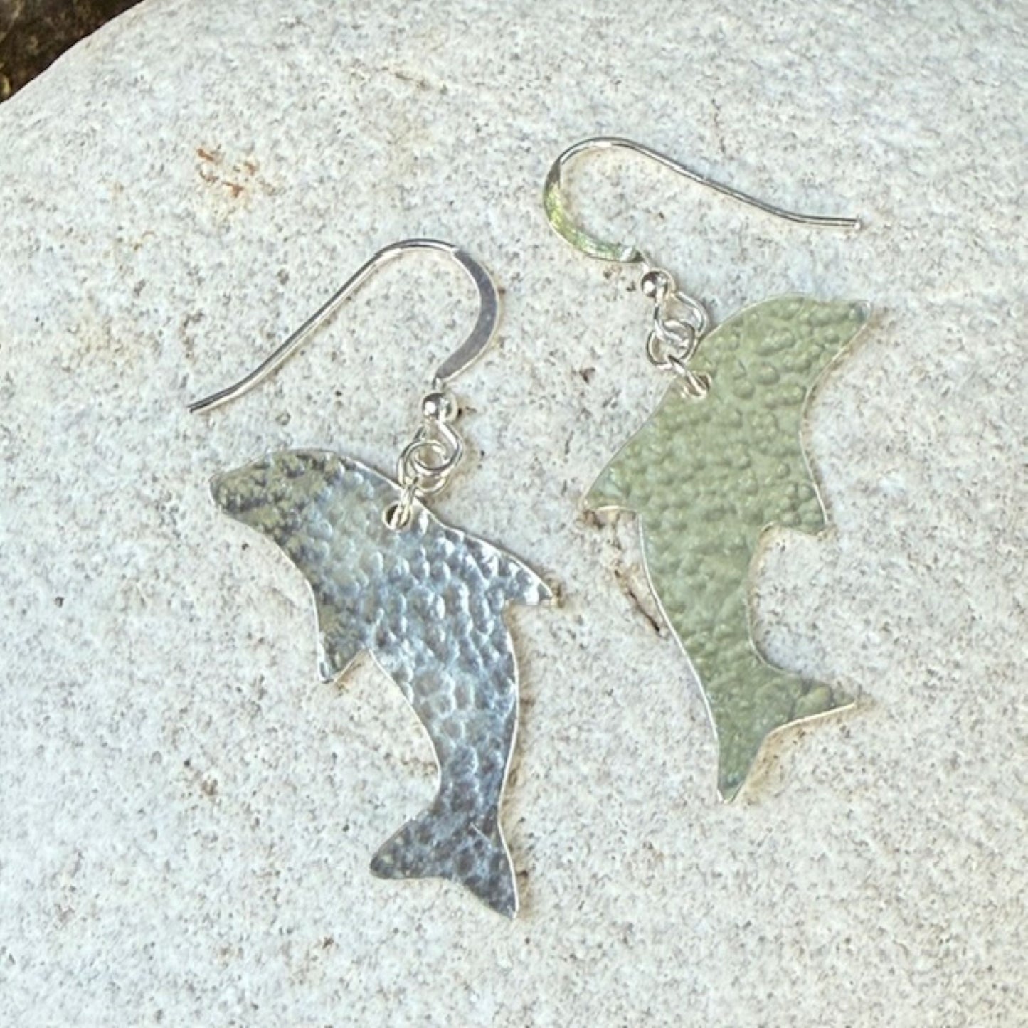 Pair of dolphin-shaped earrings on a textured surface