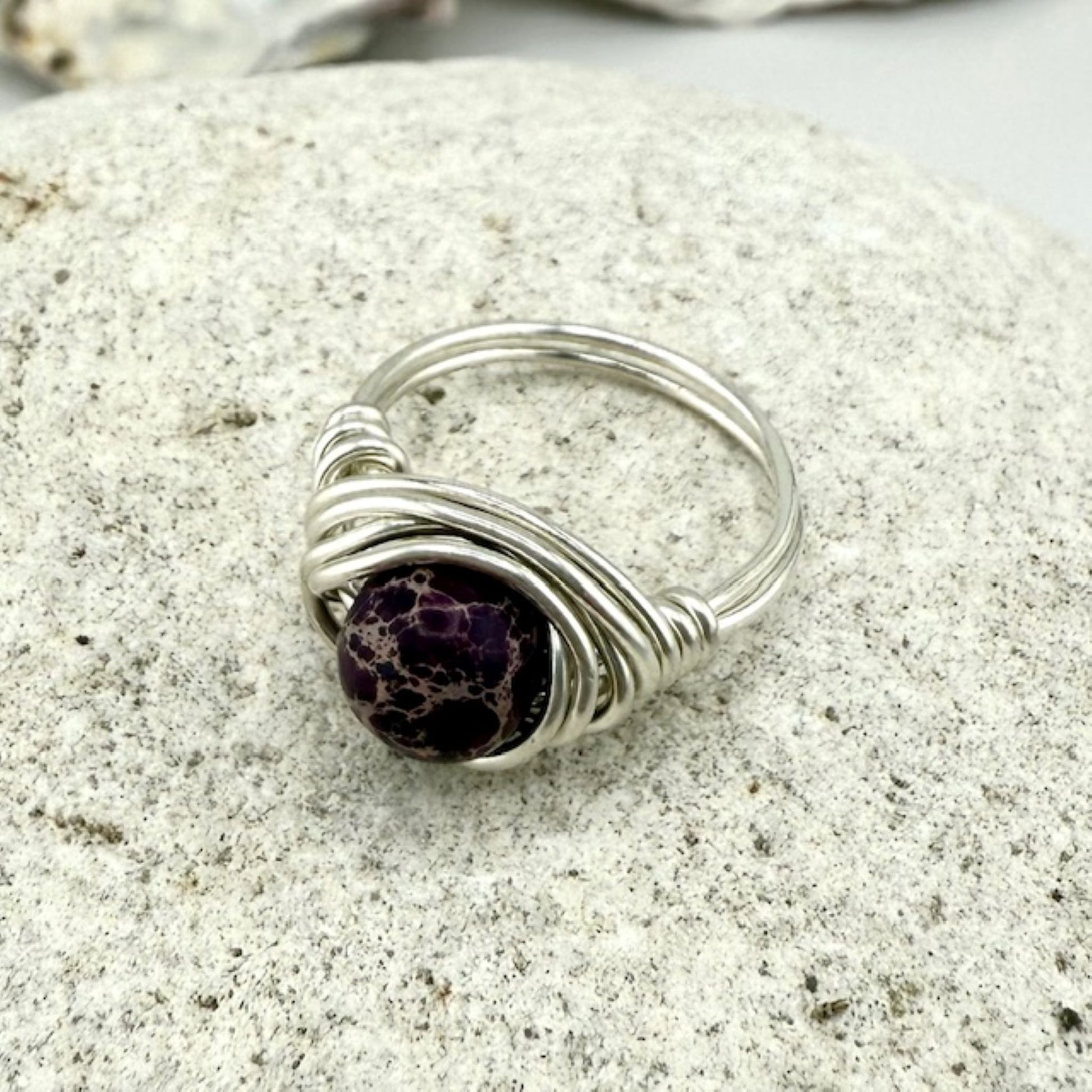 Silver ring with a purple jasper stone on a stone surface