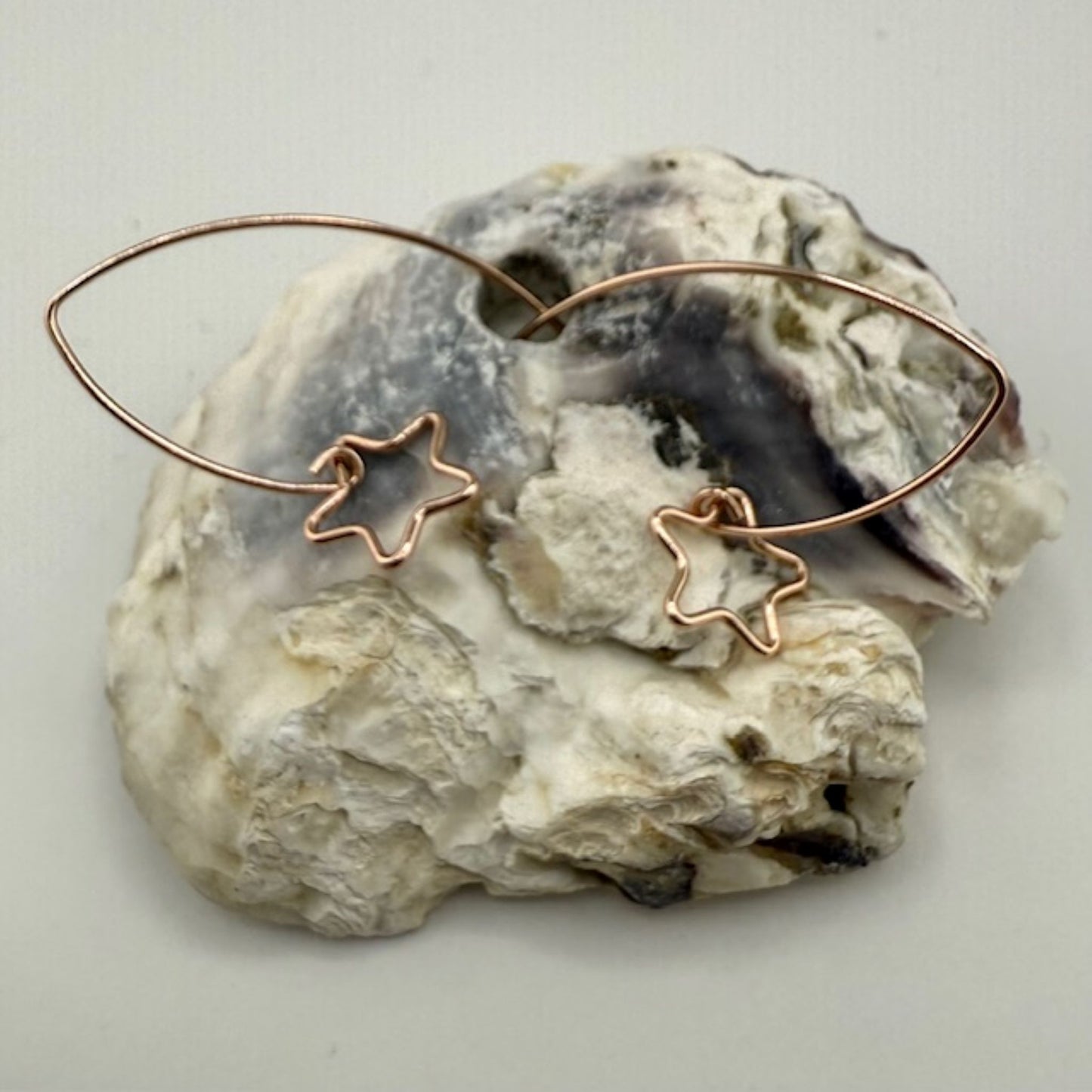 Copper star-shaped earrings on a textured stone surface