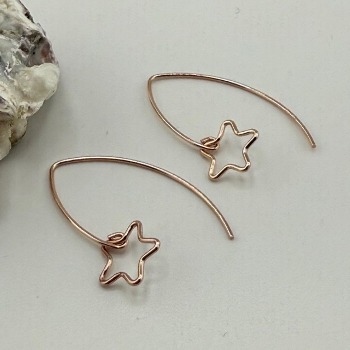 Rose gold star-shaped earrings on a light background