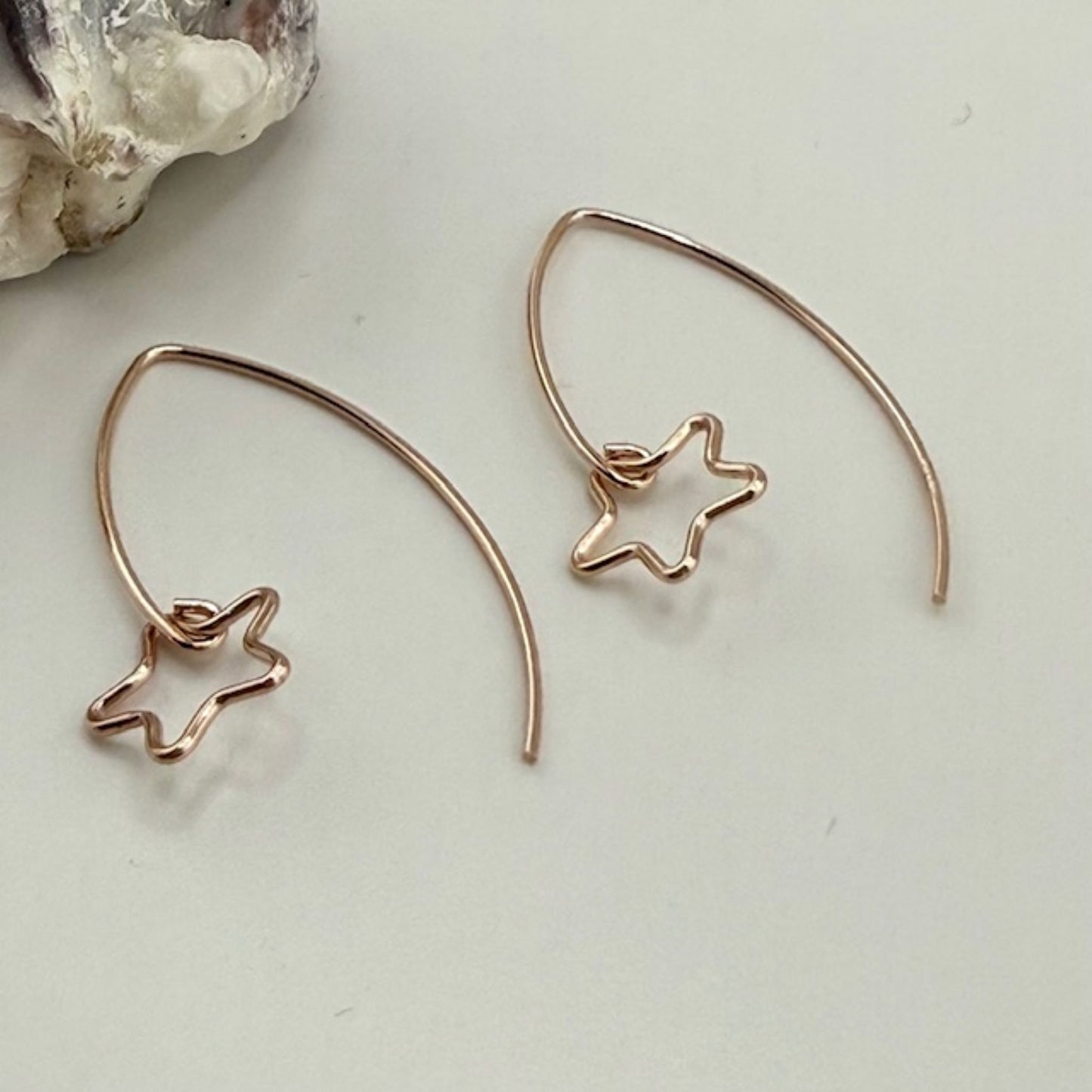 Rose gold star-shaped earrings on a light background