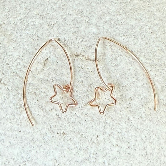 Rose gold star-shaped earrings on a light gray stone  background