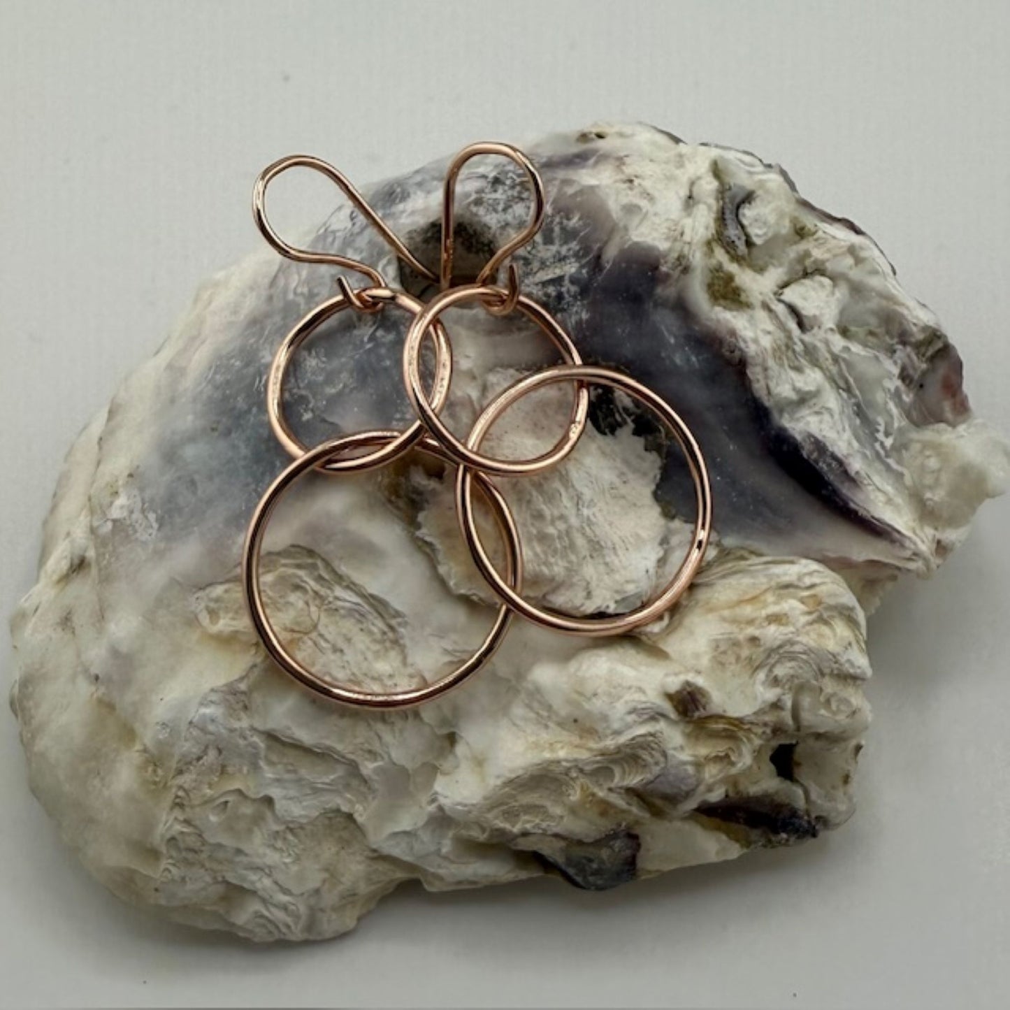 Rose gold hoop earrings on a textured stone surface