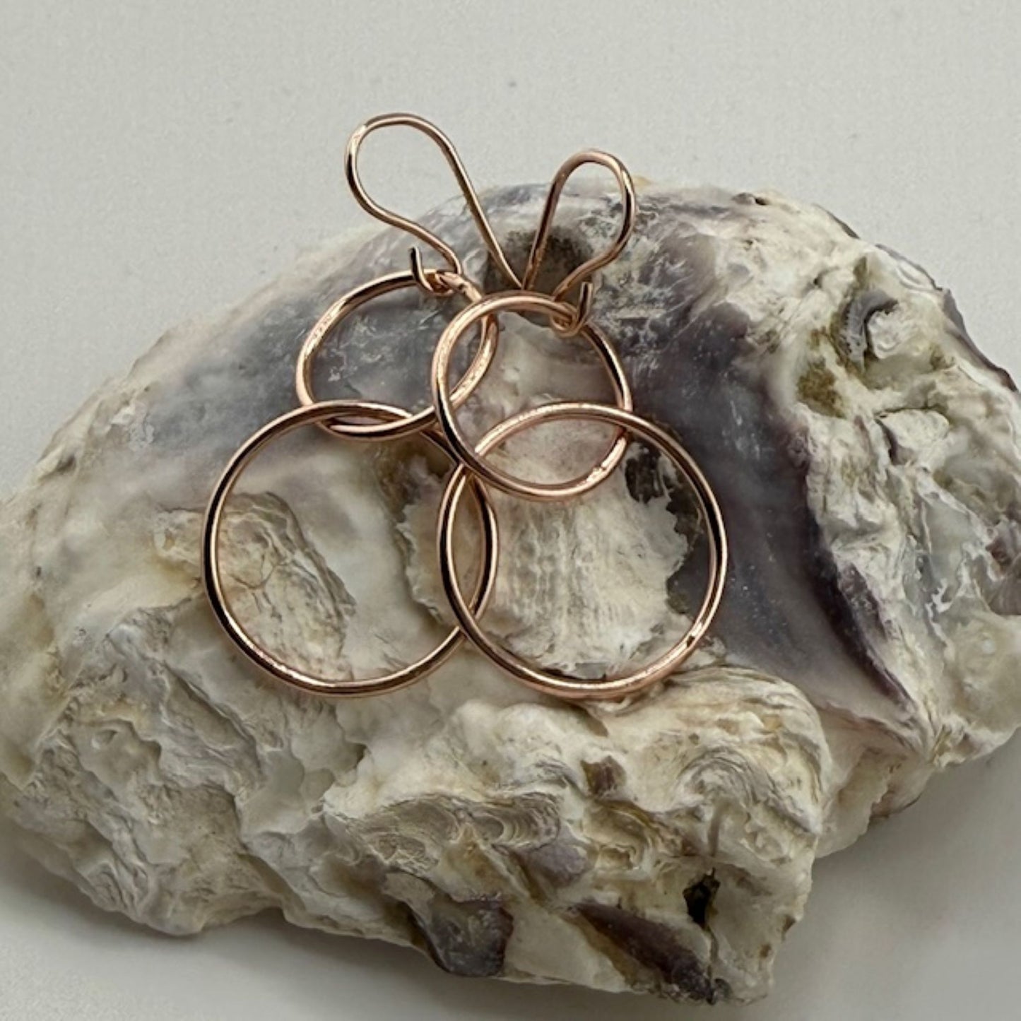 Rose gold hoop earrings on a textured stone surface