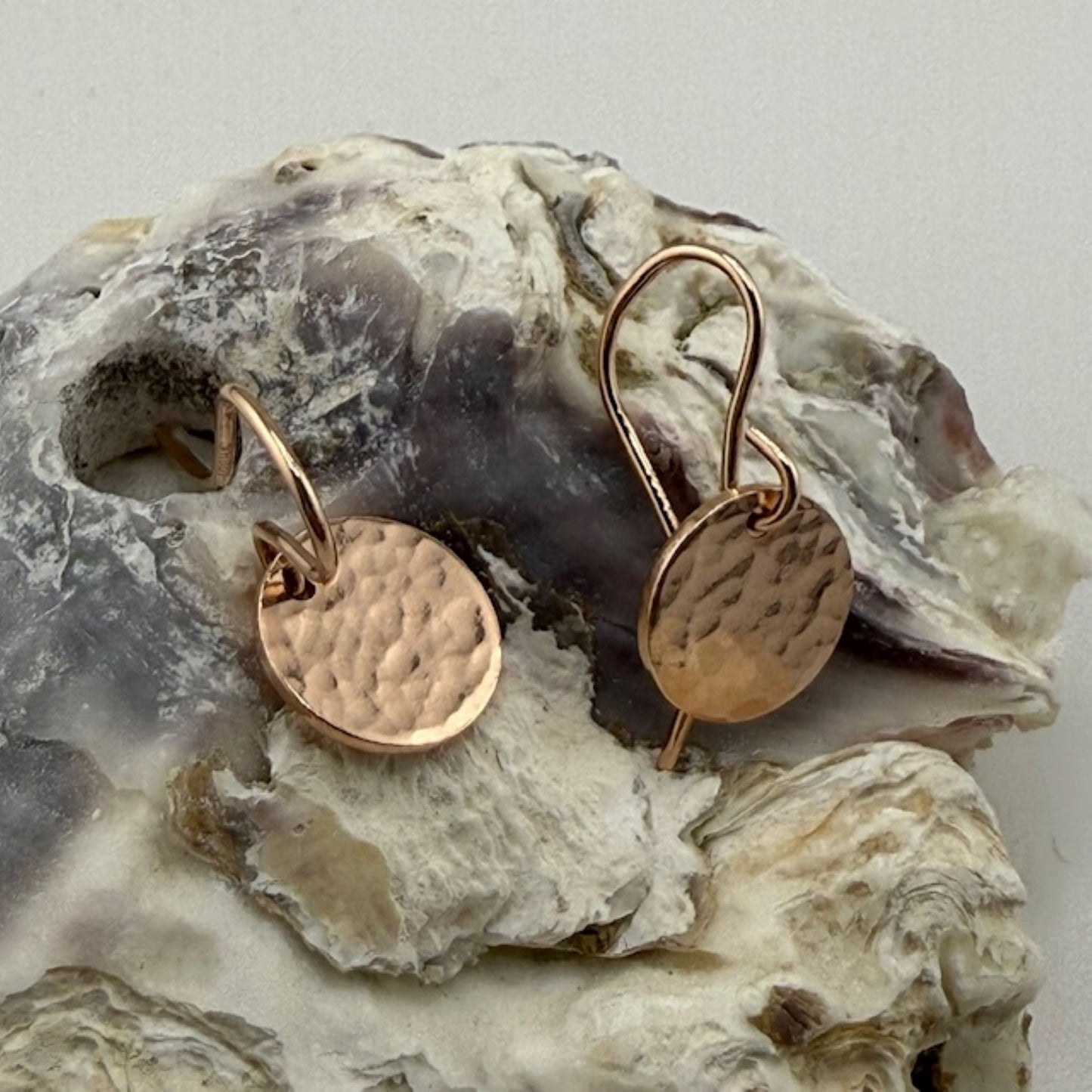 Rose gold earrings on a textured stone surface