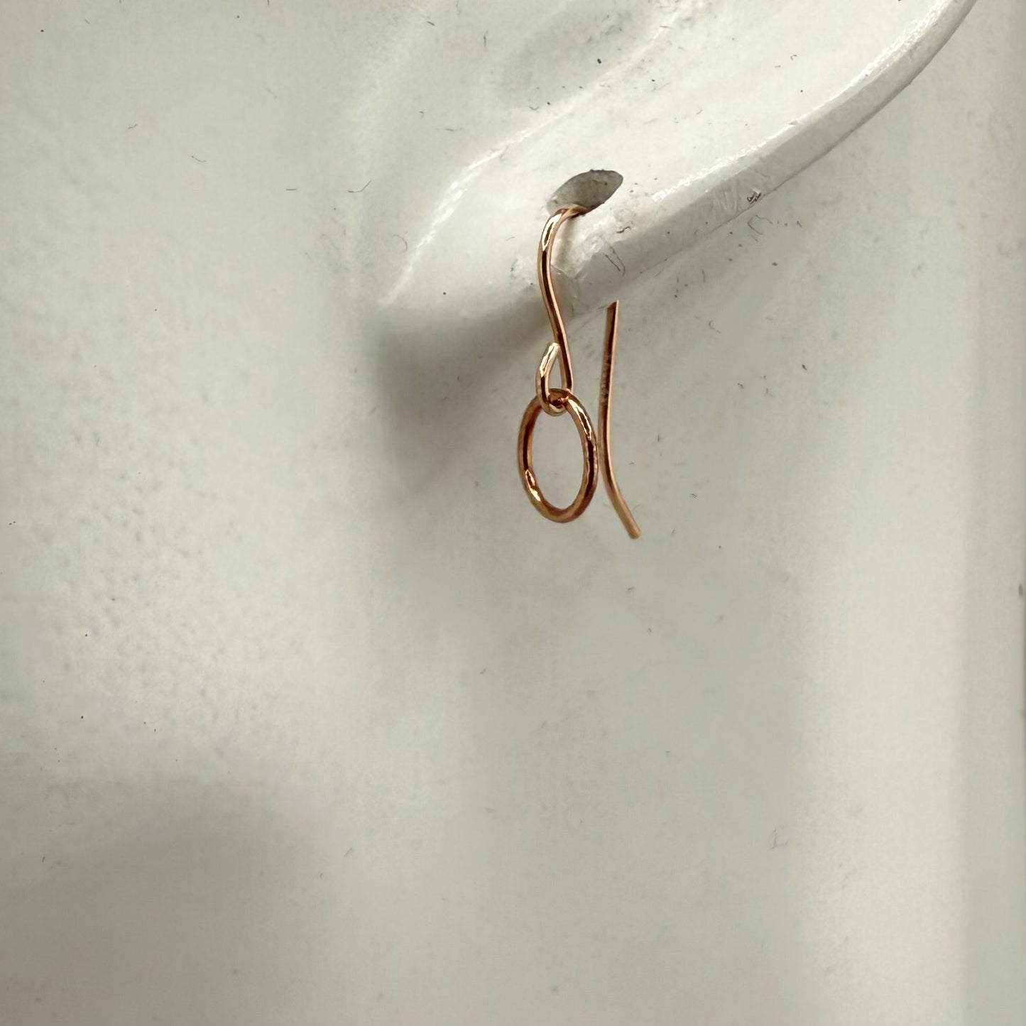 Rose gold circle hoop earring on a white ear display