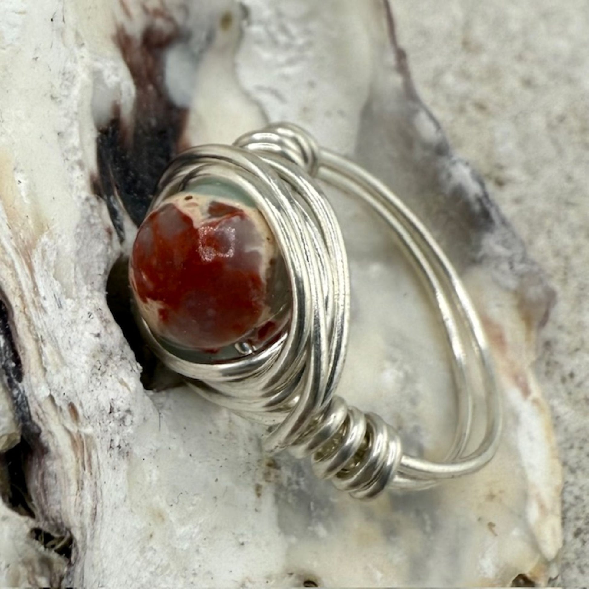 Silver ring with a sea sediment jasper stone on a textured surface