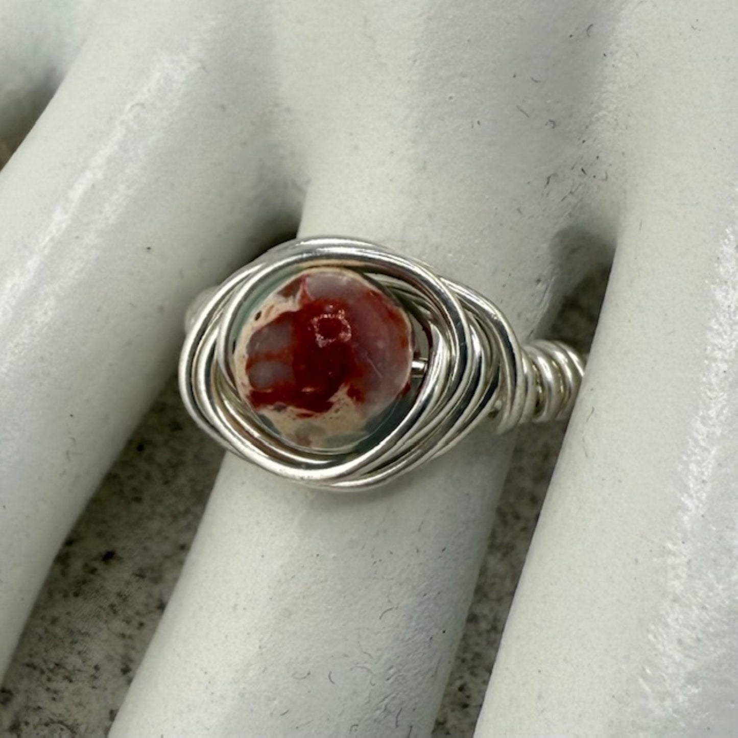 Silver ring with a sea sediment jasper stone on a white marble hand display