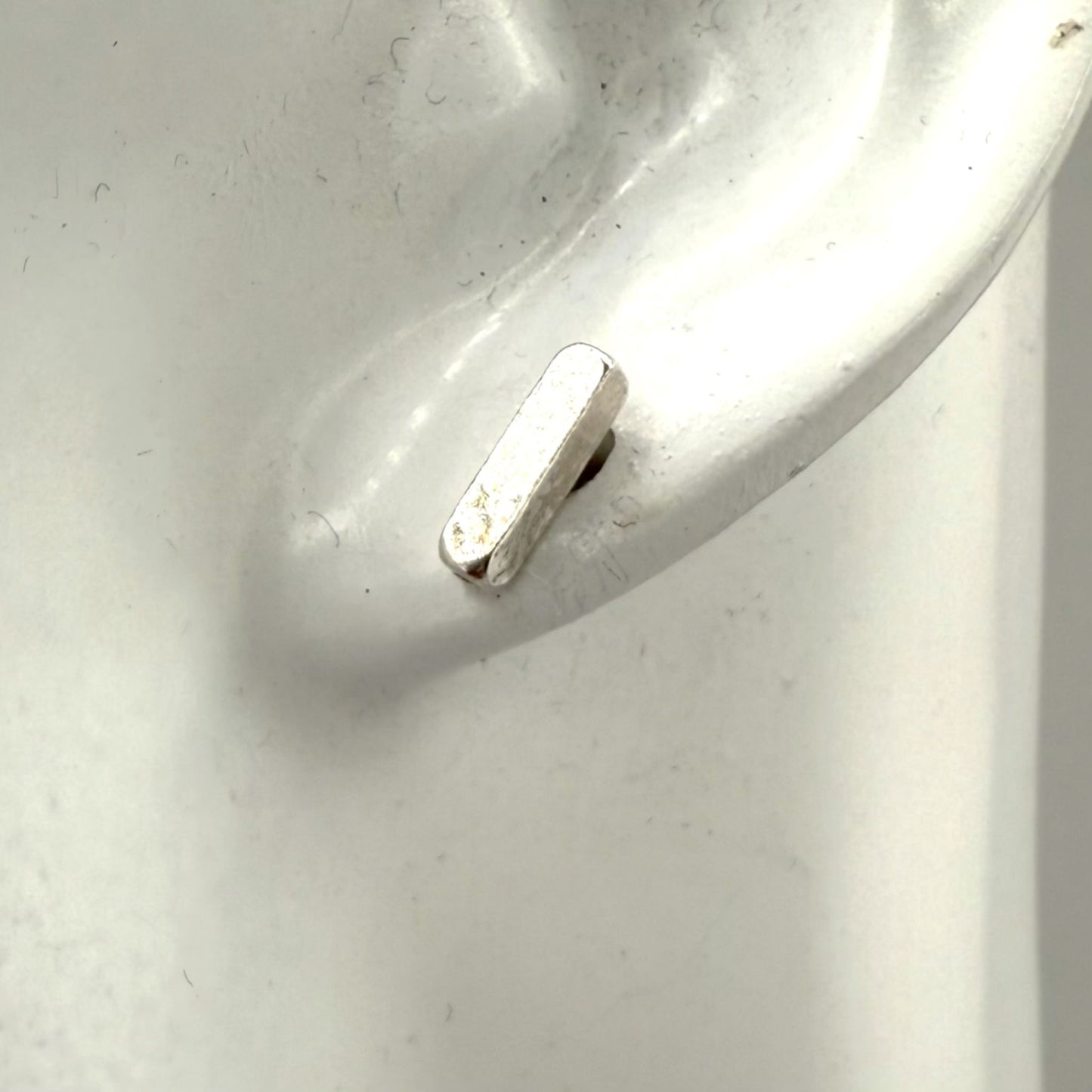 Silver earring on a white ear display
