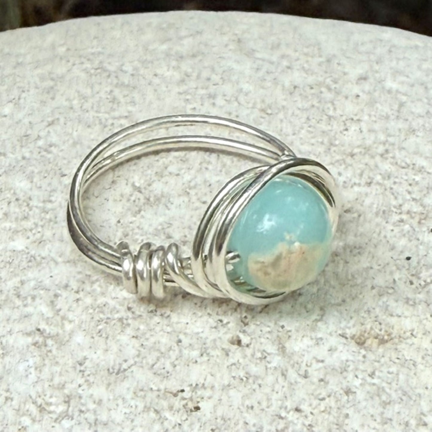Silver ring with a aqua sea sediment jasper gemstone on a stone surface