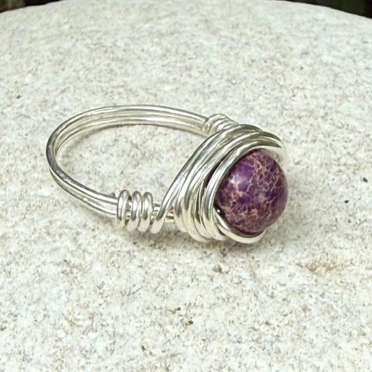 Silver ring with a purple jasper stone on a stone background