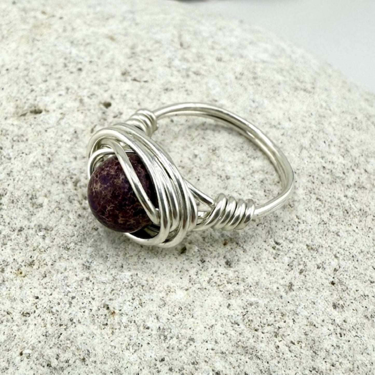 Silver and Purple Jasper Wire Wrap Ring on stone background