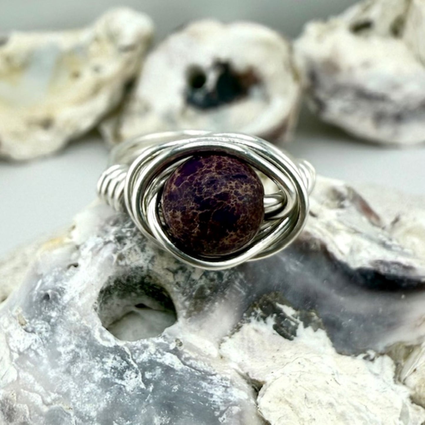 925 silver wire wrapped ring with purple jasper stone on shell background