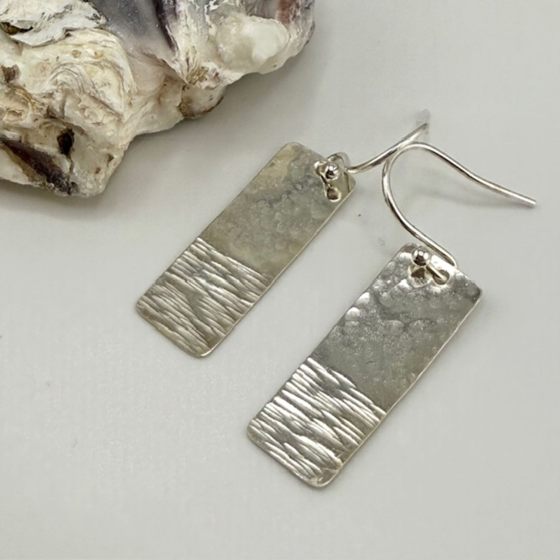 Pair of silver rectangle bar earrings on a light gray background