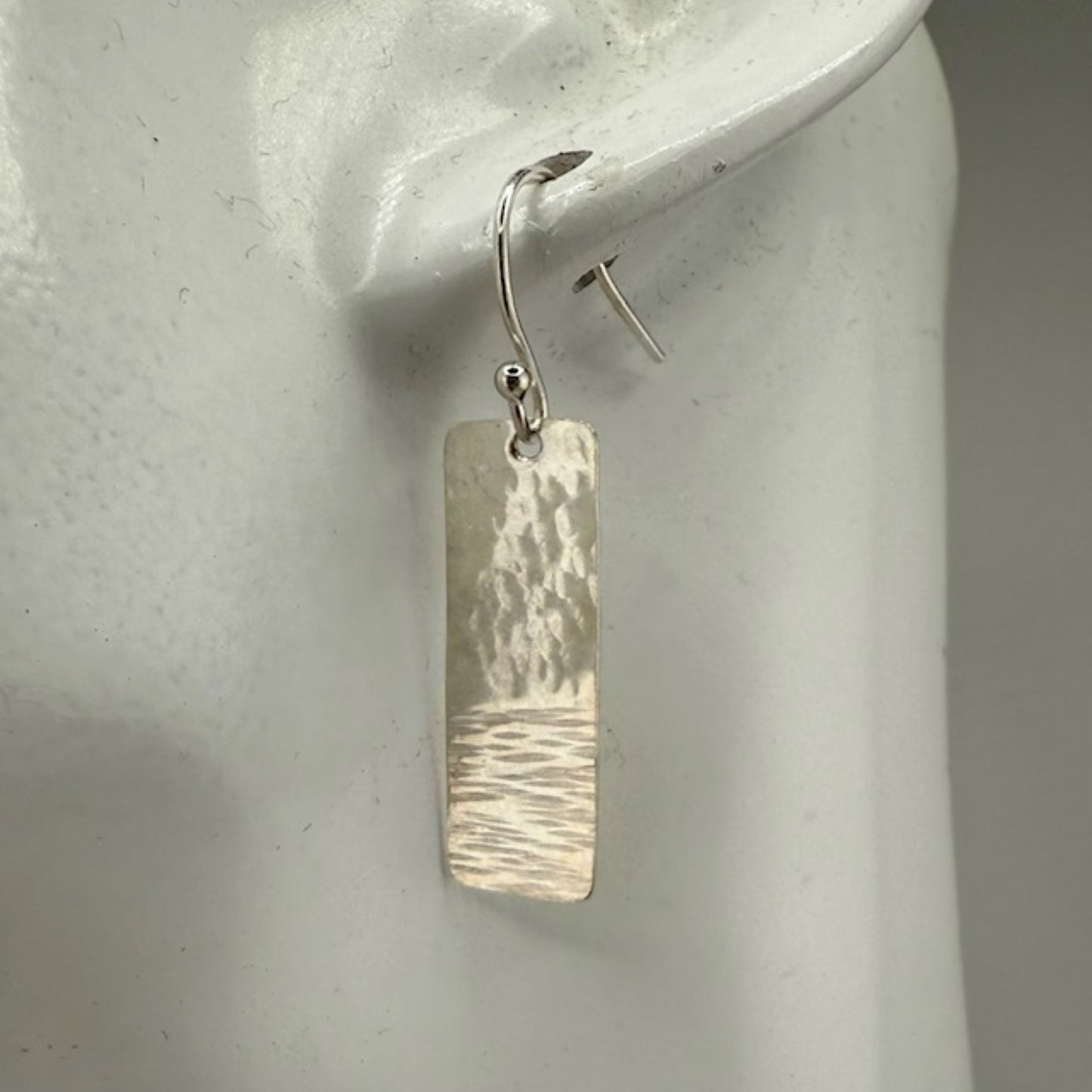 Silver bar earrings on a white mannequin ear