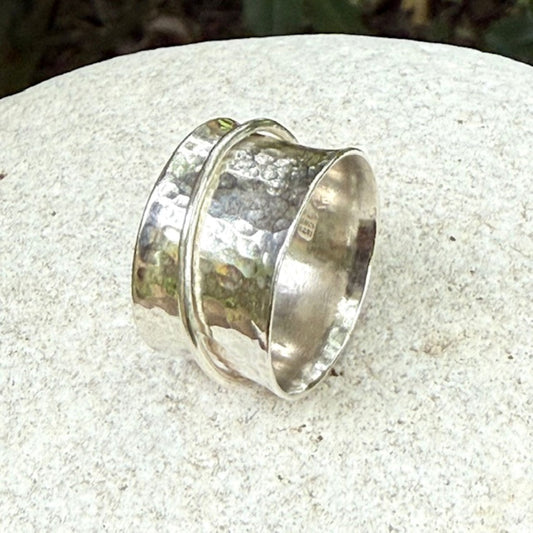Silver spinning ring with a textured design on a light stone surface