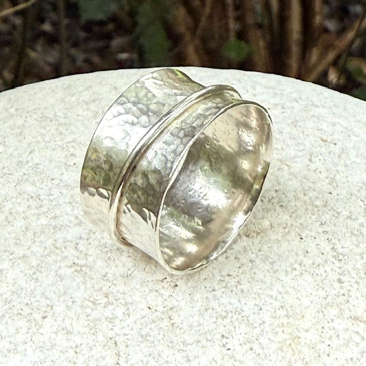 Silver spinning ring with a textured design on a light stone surface