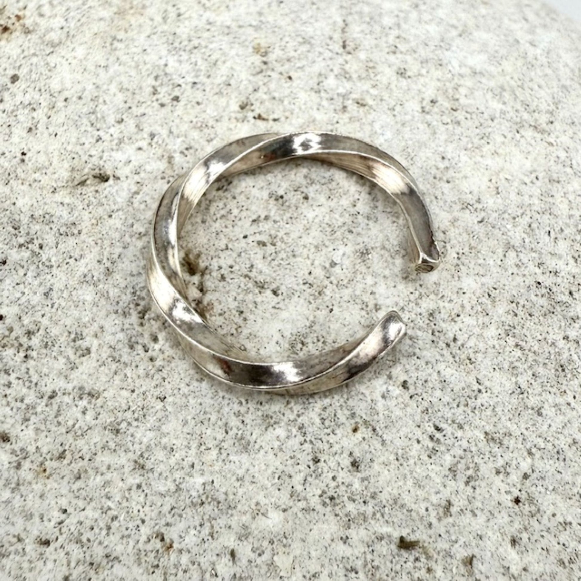 Silver twisted ring on a textured gray surface