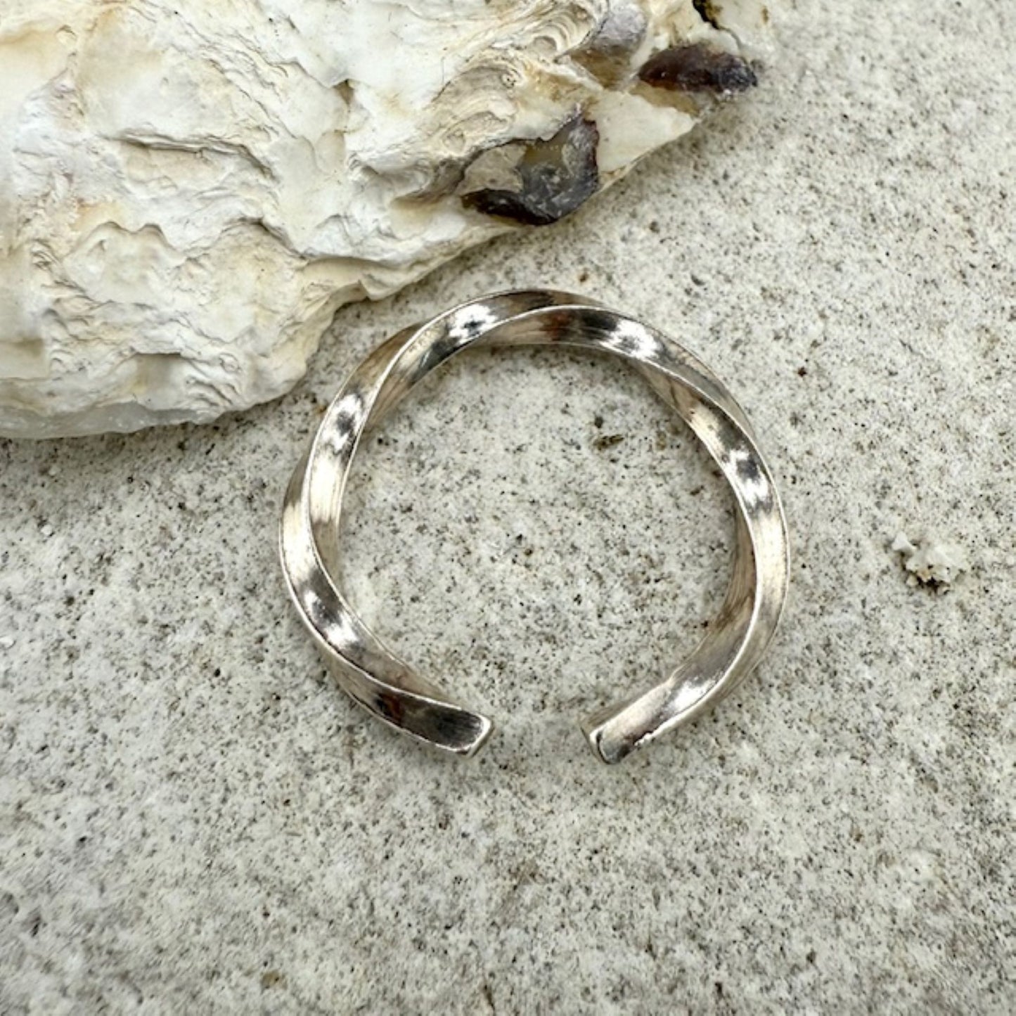 Silver ring, twisted on a natural rock background