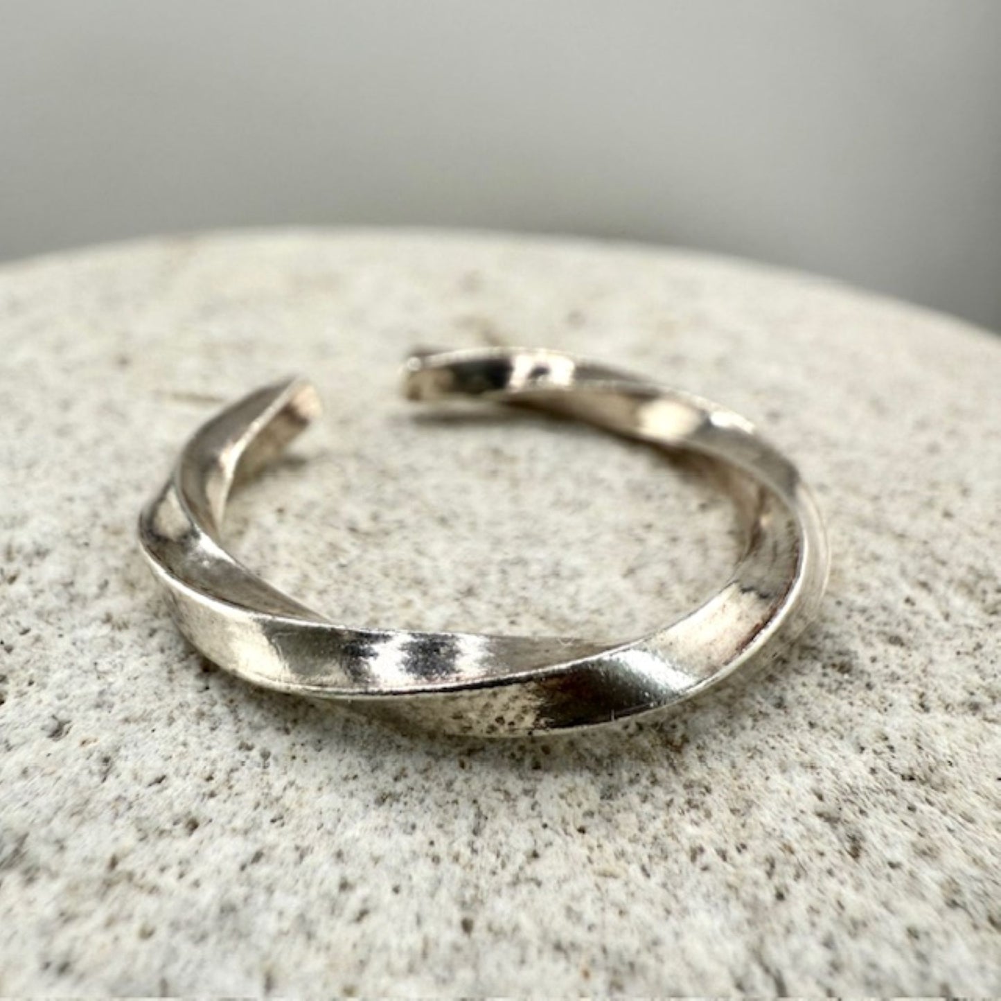 Twisted 925 sterling silver ring on a textured stone surface