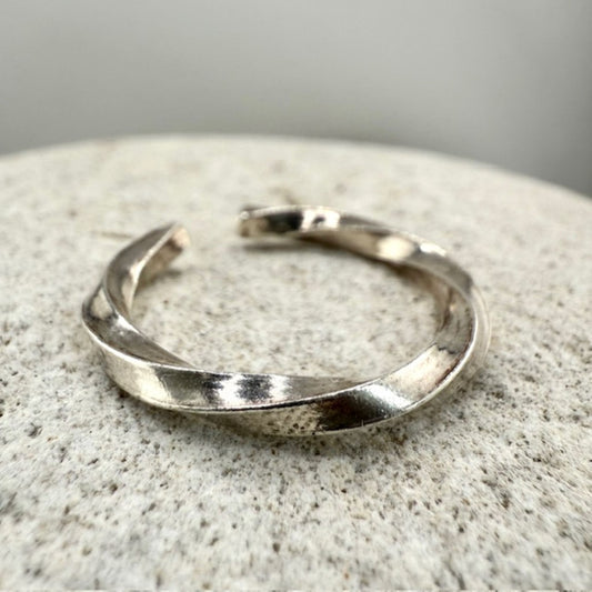 Twisted 925 sterling silver ring on a textured stone surface