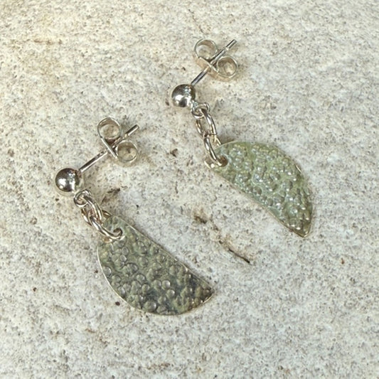 Pair of silver half moon earrings with on a textured surface