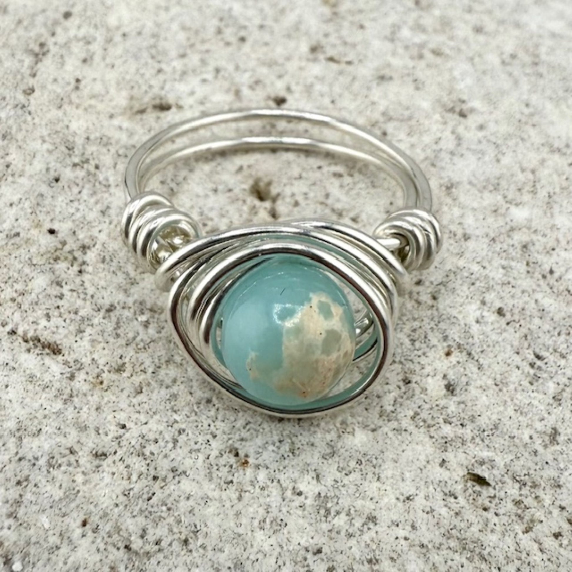 Silver ring with a blue gemstone on a textured surface
