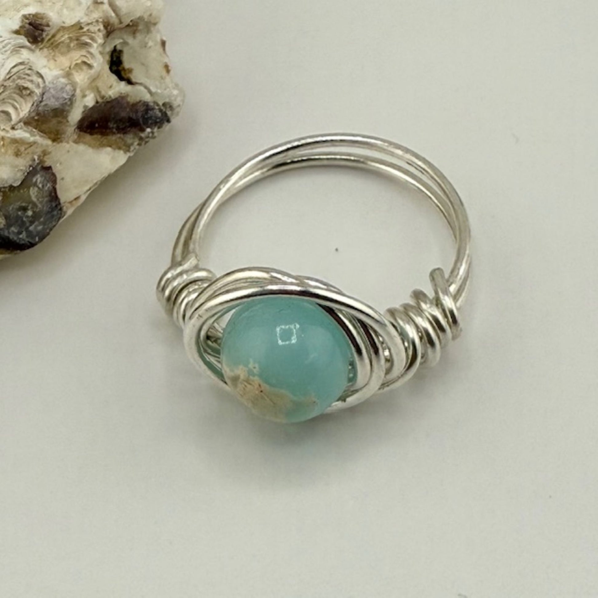Silver ring with a blue green gemstone on a light background