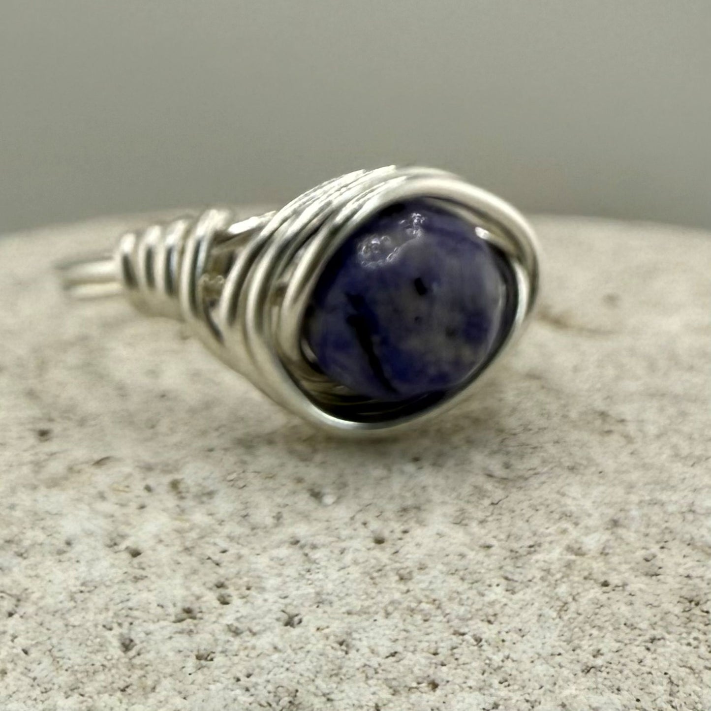 Blue lapis wire wrapped ring on a stone surface
