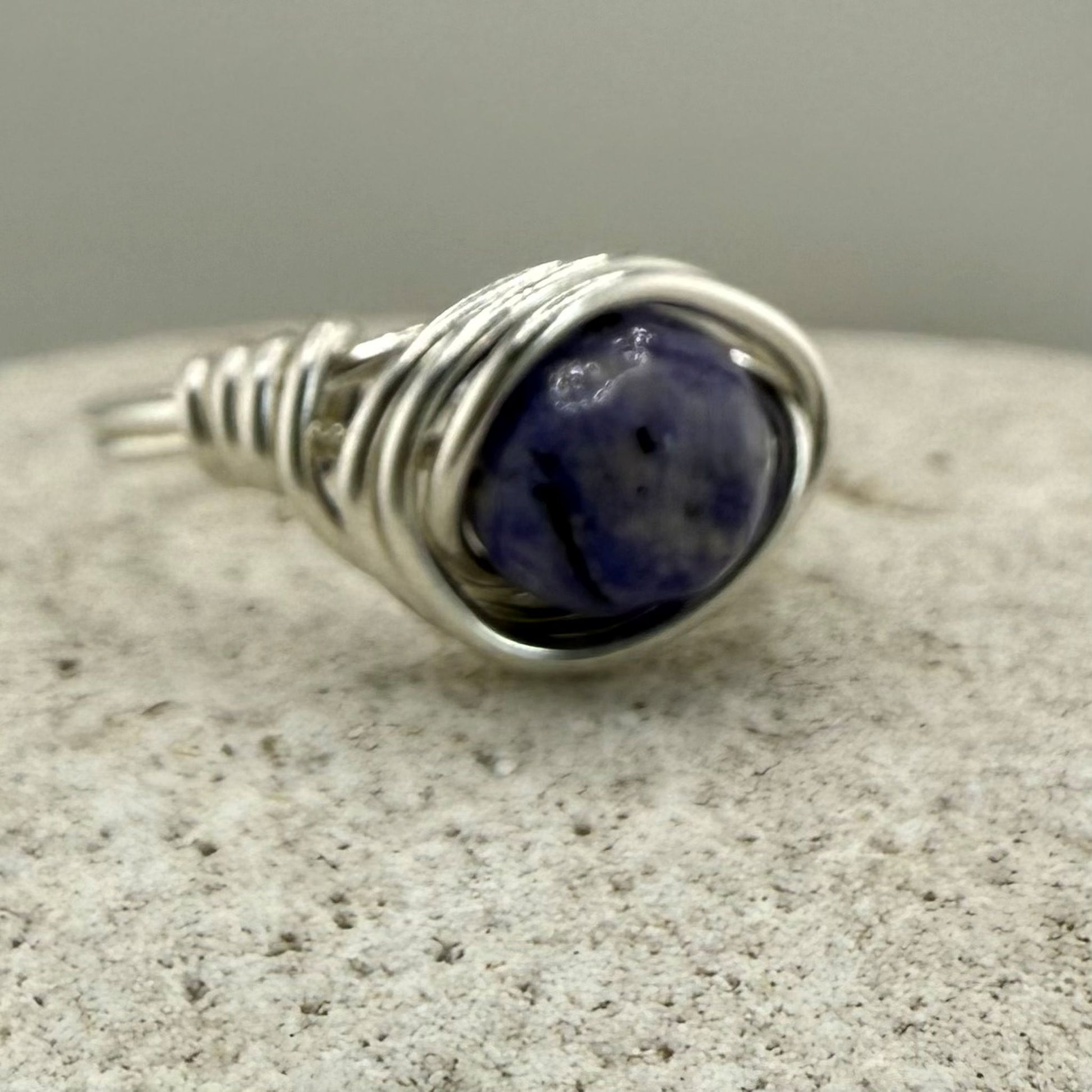 Blue lapis wire wrapped ring on a stone surface