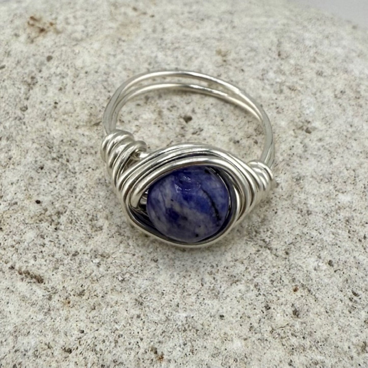 Round lapis lazuli gemstone ring on a stone background