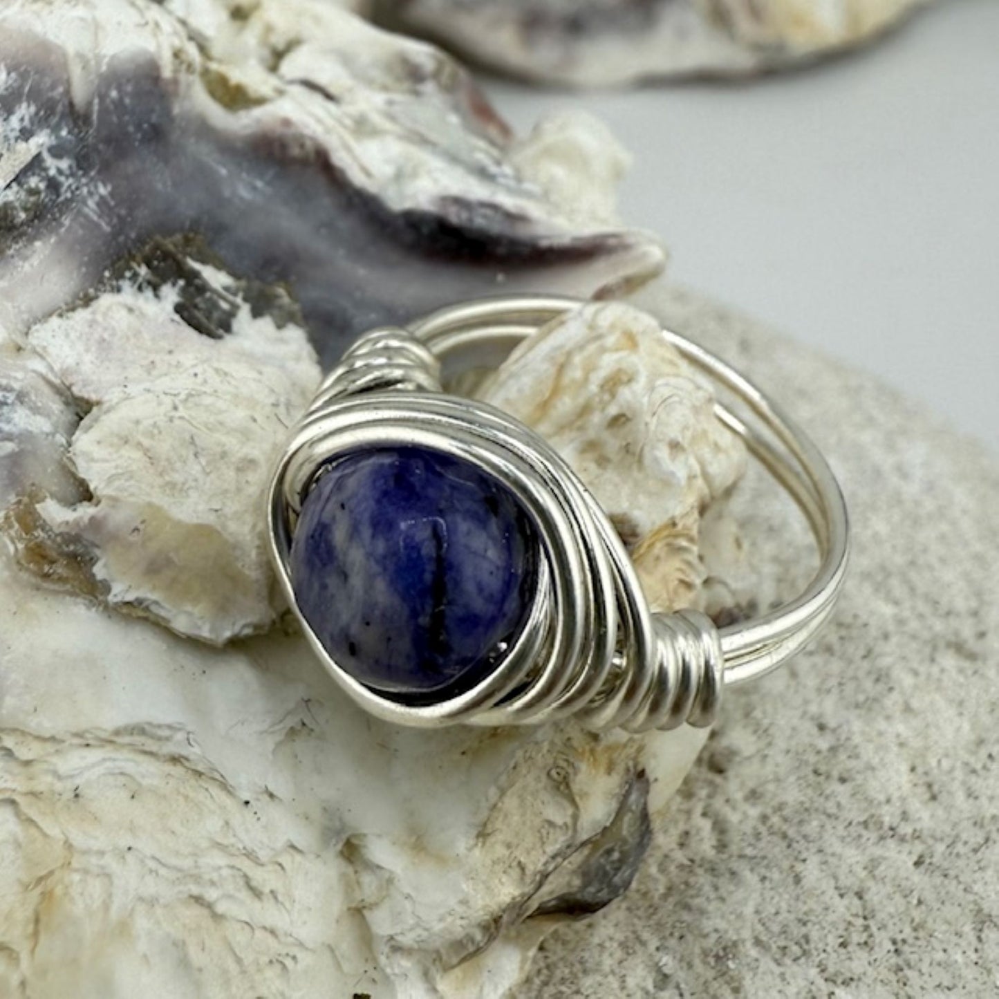 Silver ring with a blue stone on a textured surface