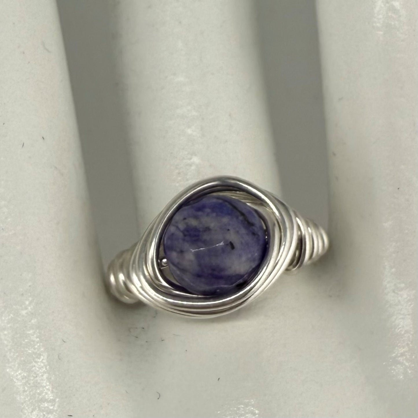 Silver ring with a blue stone on a white marble hand display