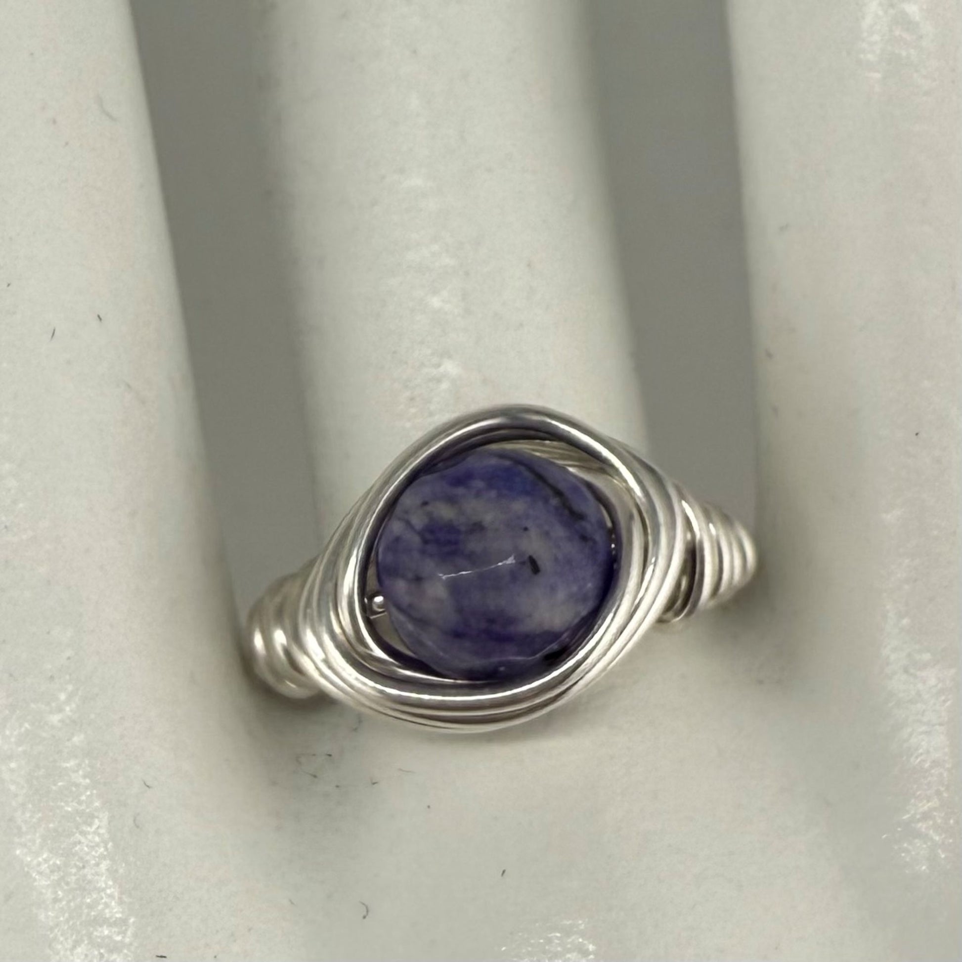 Silver ring with a blue stone on a white marble hand display