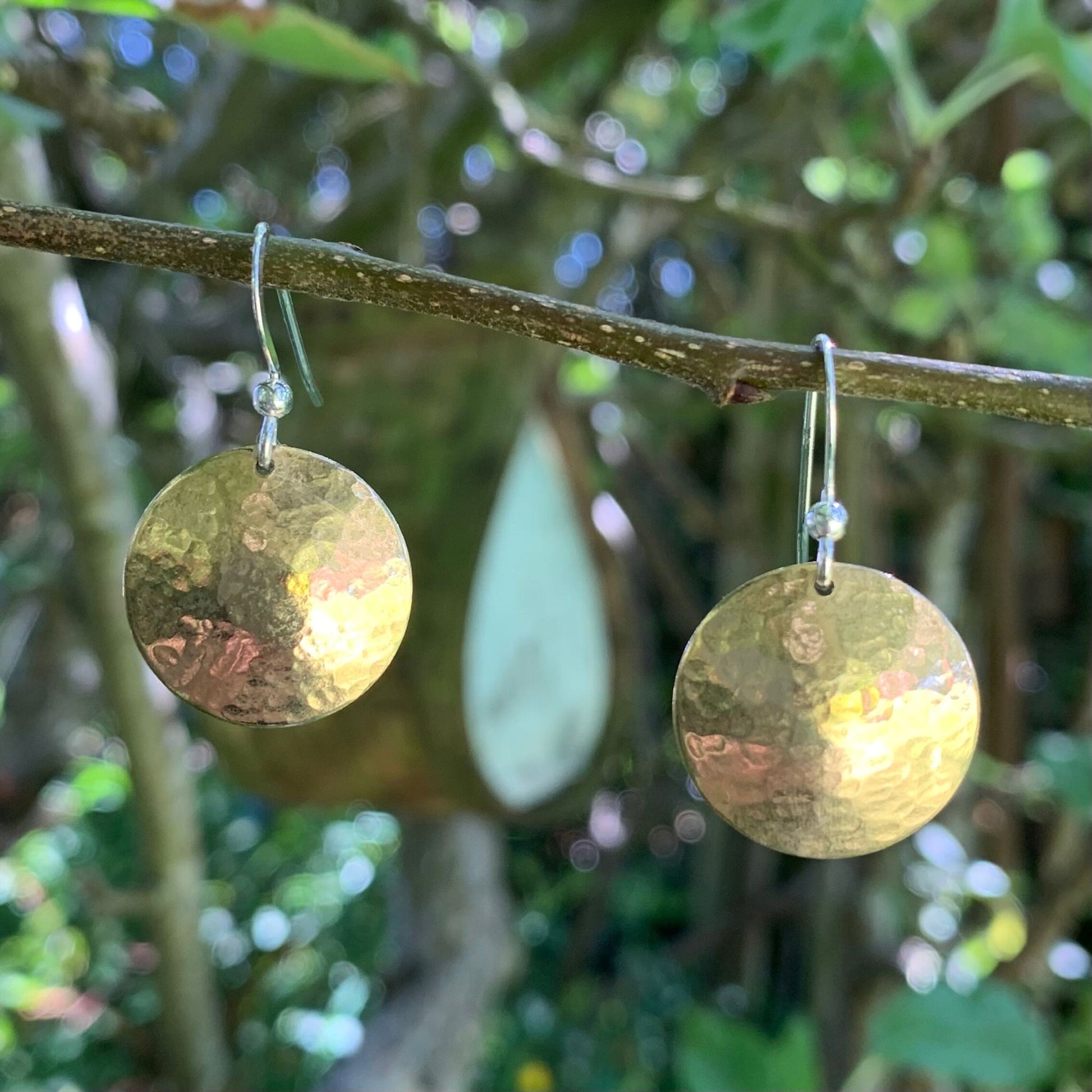 Gold earrings hanging on a branch with a natural background