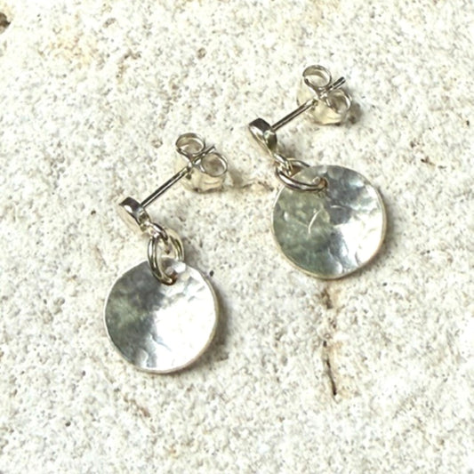 Silver round stud earrings on a textured stone surface