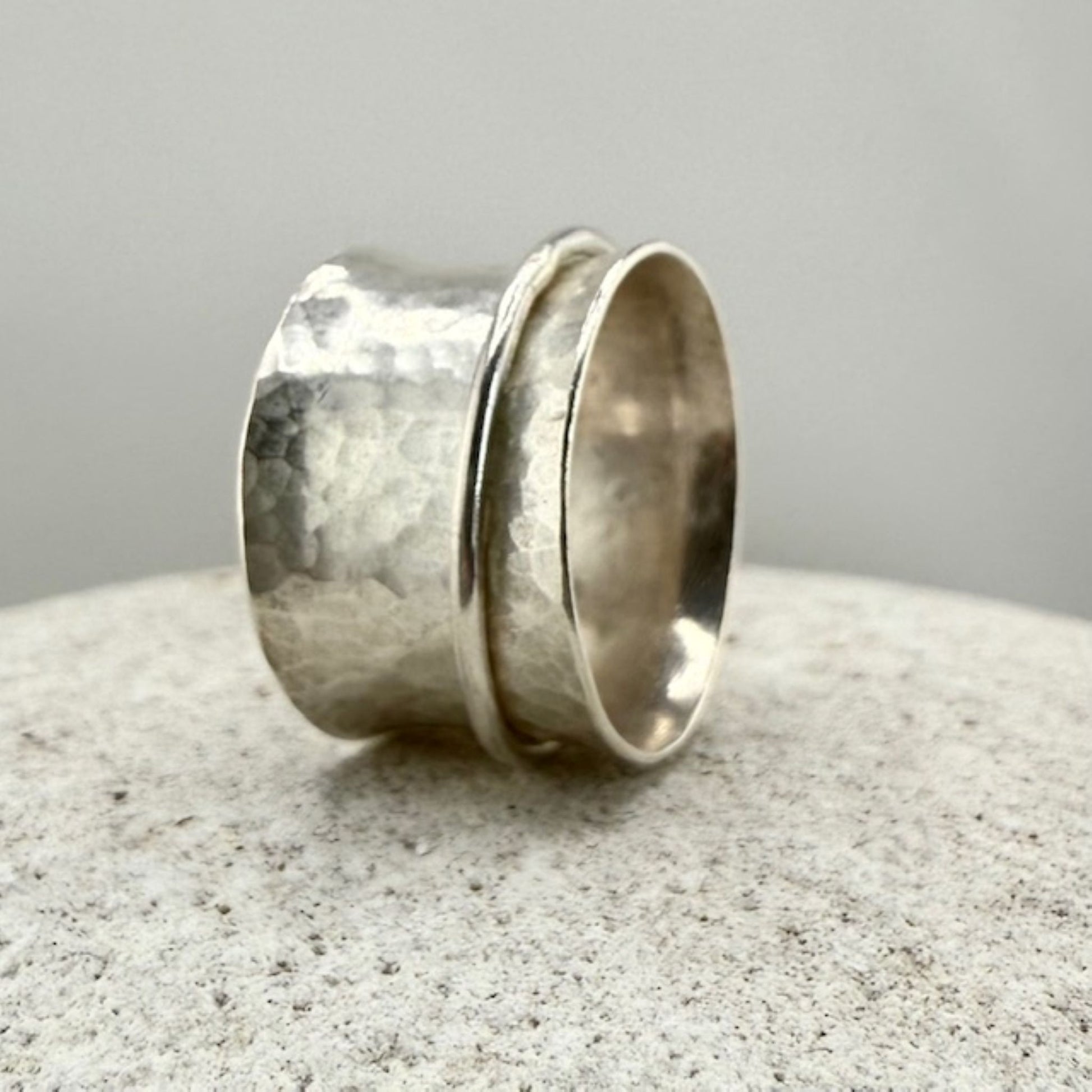 Sterling Silver spinner ring with textured surface on a natural stone