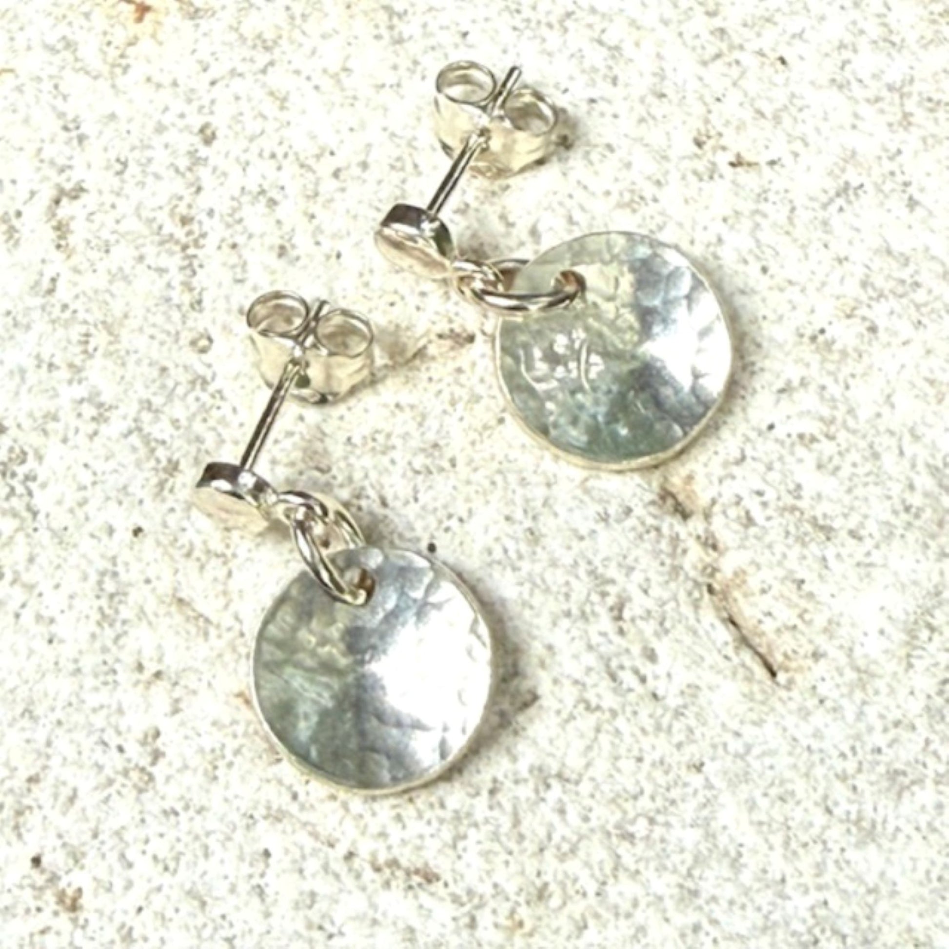 Silver earrings with round pendants on a textured surface